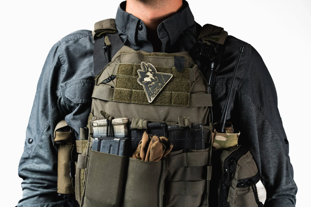 Dirty Civilian Logo Patch worn on an olive plate carrier, triangular PVC design with green and black dog-head logo