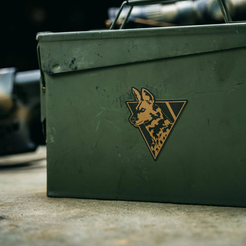 Dirty Civilian African Painted Dog logo sticker in tan and black applied to a weathered olive-green metal ammo can