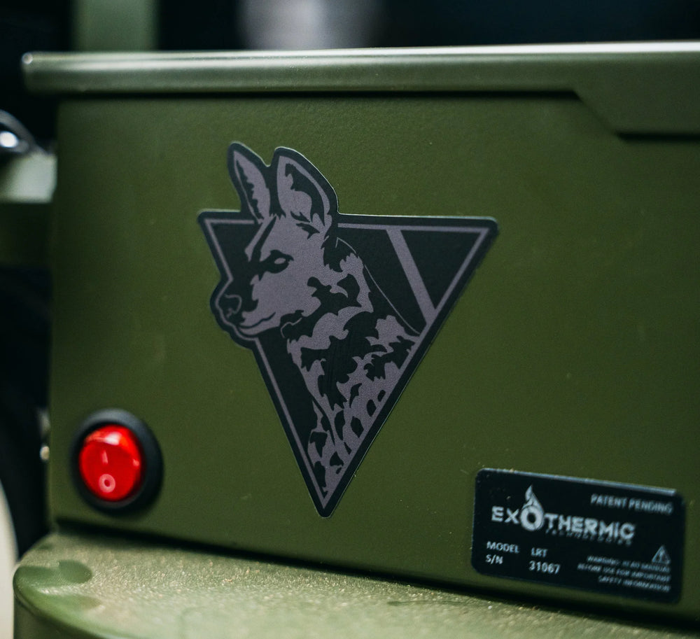 Dirty Civilian African Painted Dog triangle sticker in gray and black applied to an olive green ammo can, lifestyle close-up