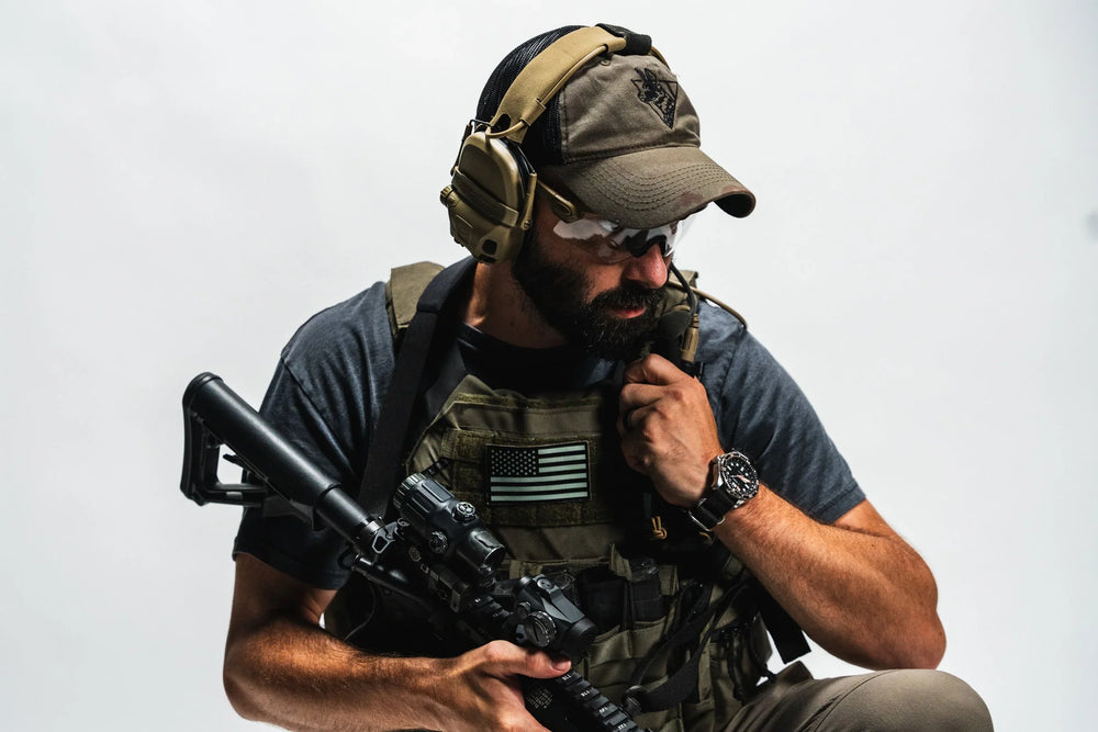 Olive Team Cap worn on-body by bearded man in tactical gear, embroidered painted dog logo, ear-pro over the crown