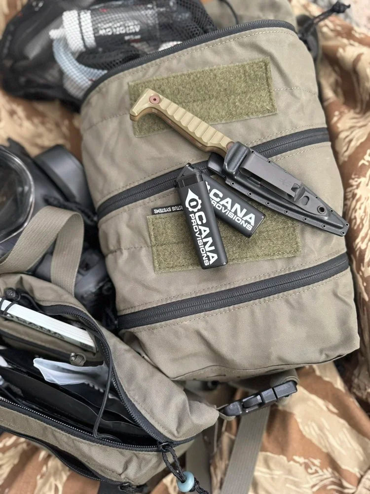 Black CANA MK torch pocket lighter with white CANA Provisions logo, resting on olive tactical gear in a lifestyle flat-lay